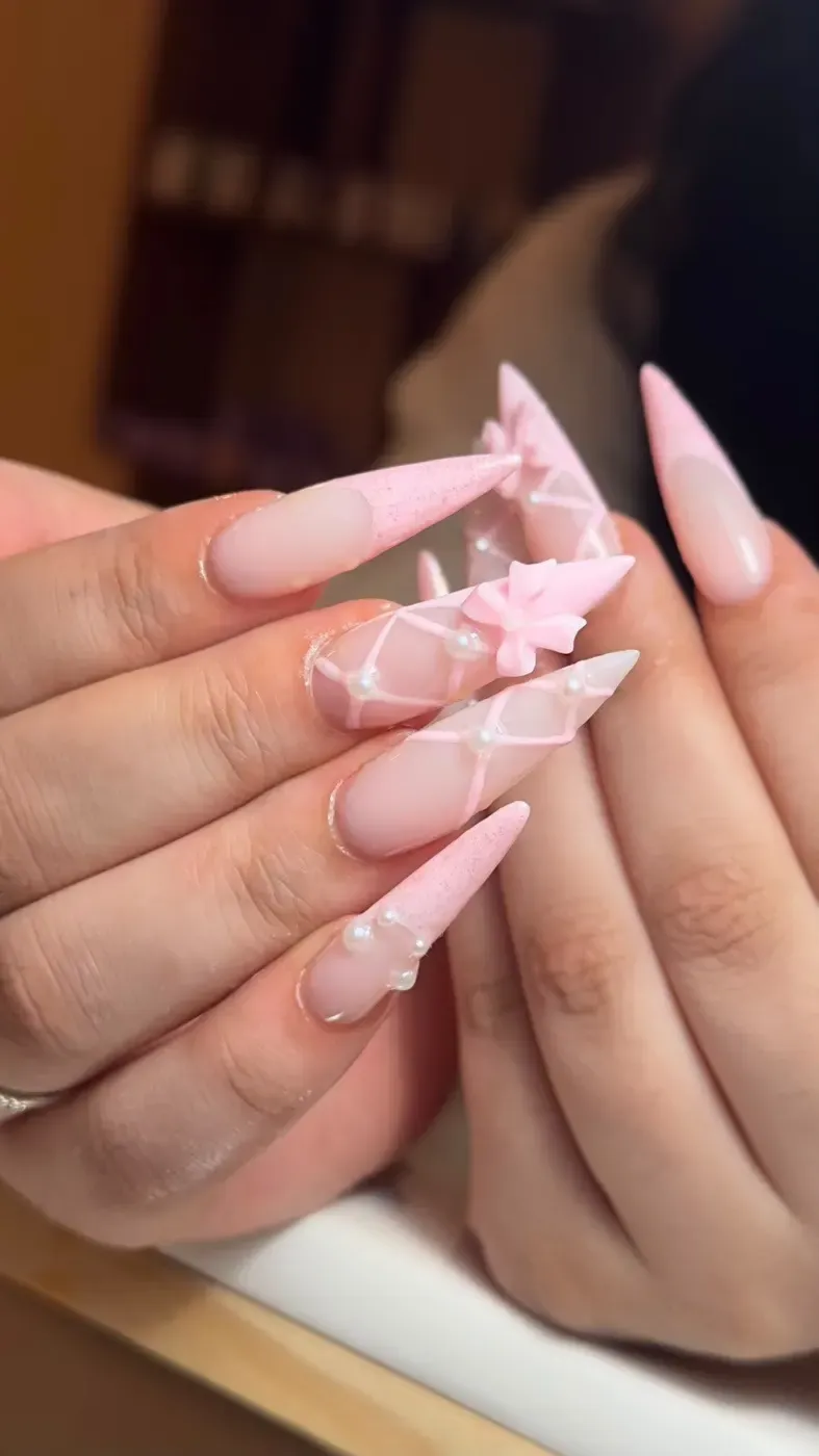 Lange roze acrylnagels met 3D-strikjes